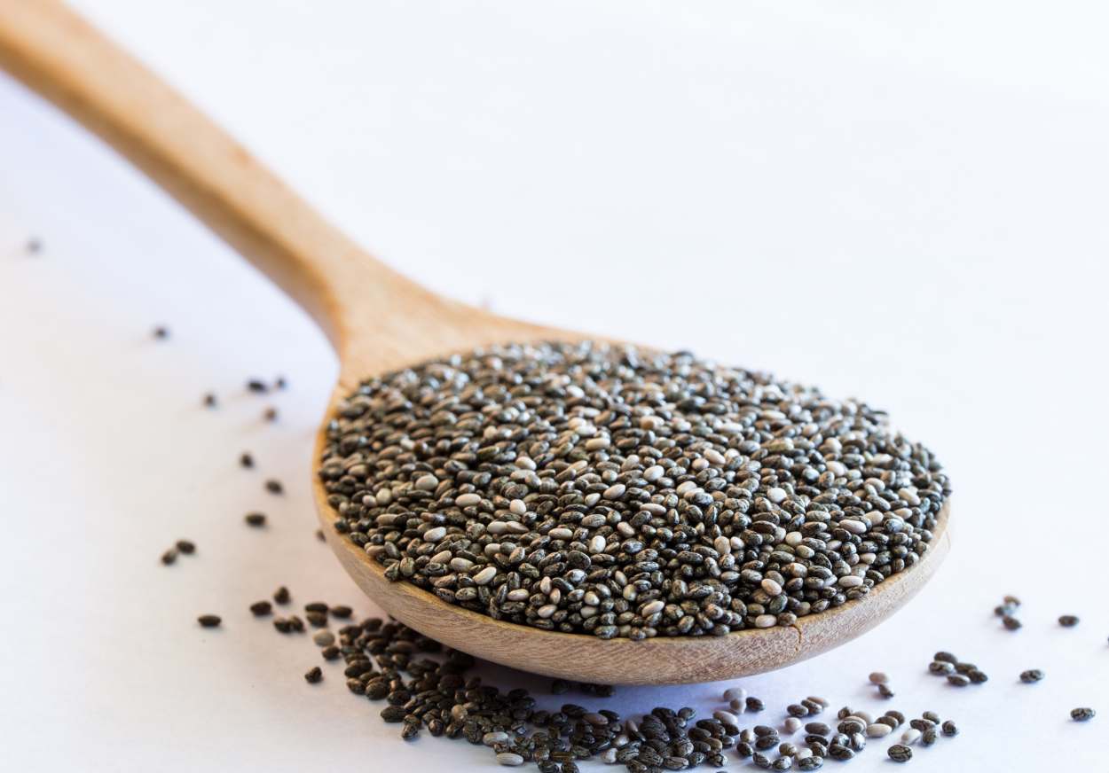 A spoonful of chia seeds on a white background.