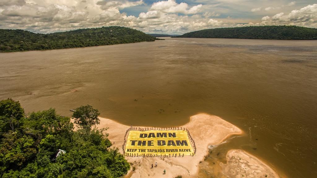 Más de cien miembros de la comunidad Munduruku incluyendo a líderes guerreros y niños desplegaron junto a Greenpeace un cartel de 20X30 metros sobre la playa en una sección considerada sagrada del río Tapajós en el Amazonas con el mensaje: "Maldita la represa: mantengan vivo al río Tapajós"