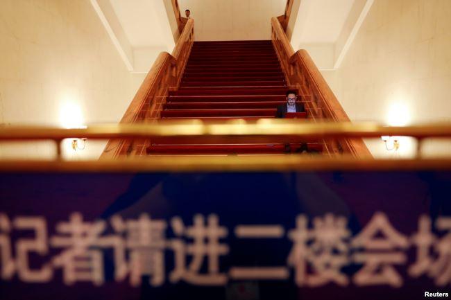 全国人大会议投票表决通过修宪案后，一名记者坐在北京人大会堂的台阶上工作。（2018年3月11日）
