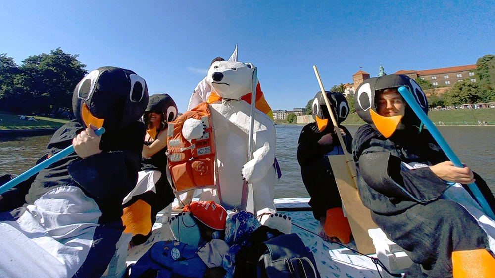 Rebels row a boat dressed in penguin costumes. A polar bear with life jackets sits at the end of the vessel