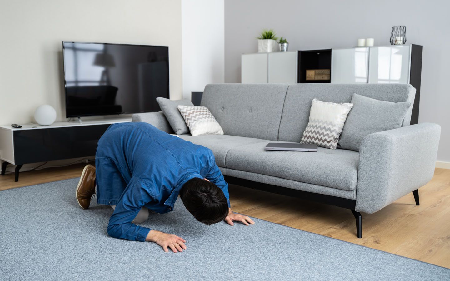 Benefits of minimalist living: man looking for something under the sofa