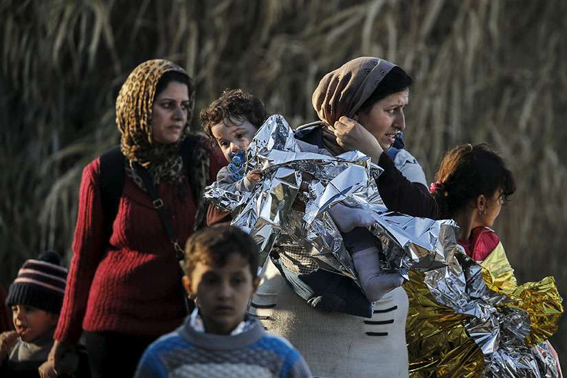 A Syrian refugee carries her child in a thermal blanket as refugees and migrants arrive on an overcrowded boat on the Greek island of Lesbos, 2015. CNEWA's $150 million contributed to Iraq and Syria in 2015 was only second to the United Nations'.