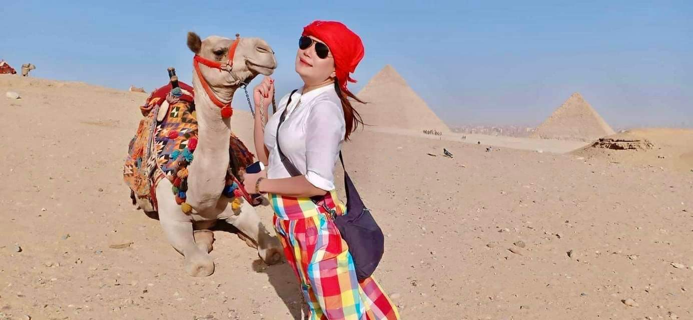 Image of Candy with a camel, with the pyramids of Giza in the background