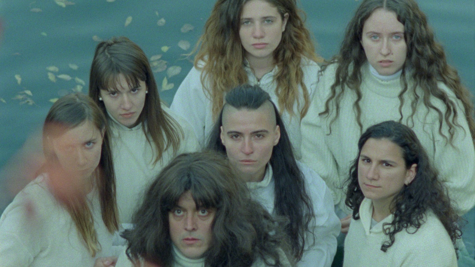 From the film Mammalia, a group of long-haired people, wearing all white, look up at the camera above.