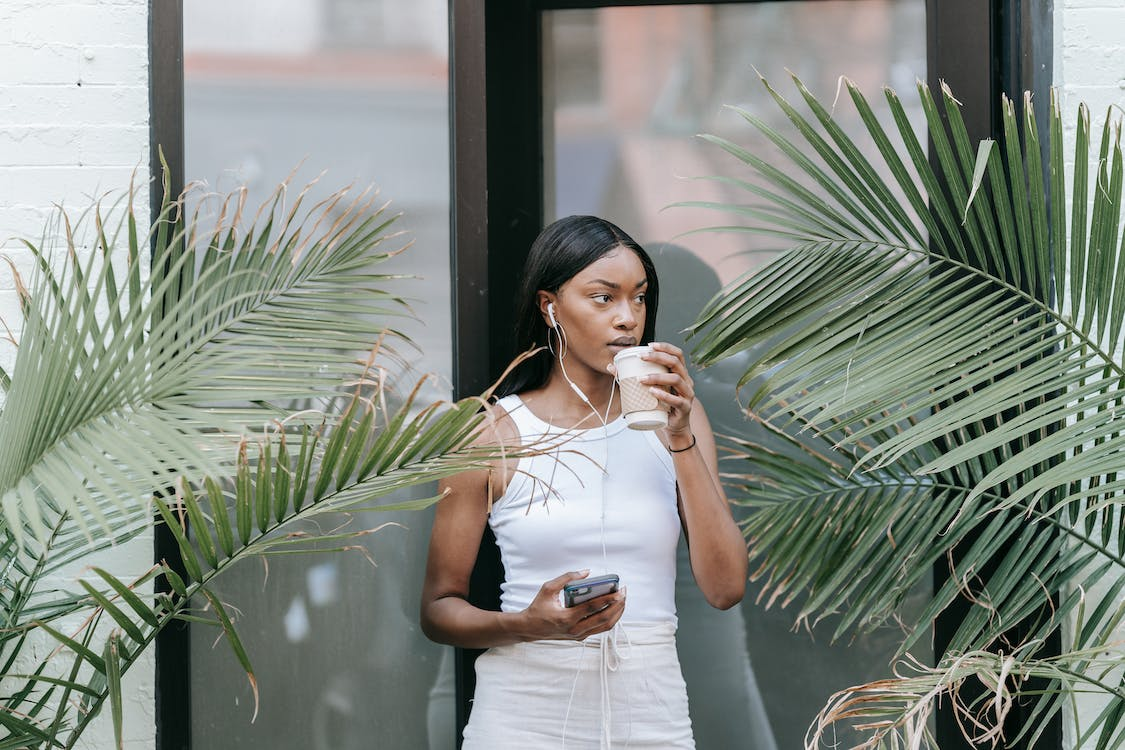 a woman walking out of a coffee shop with a drink
