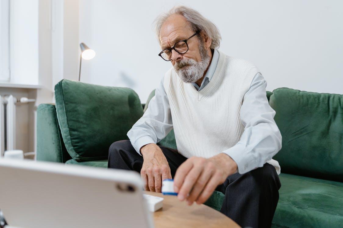 Man in White Dress Shirt and Black Pants Sitting on Green Couch