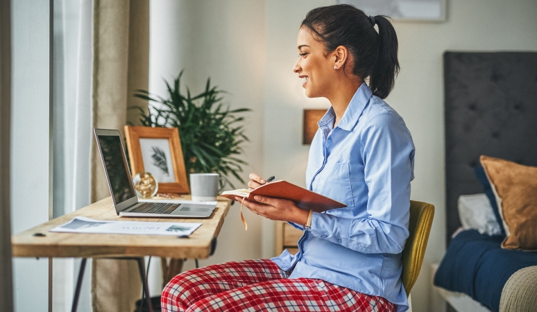 a woman working from home in a dress shirt and pajama pants