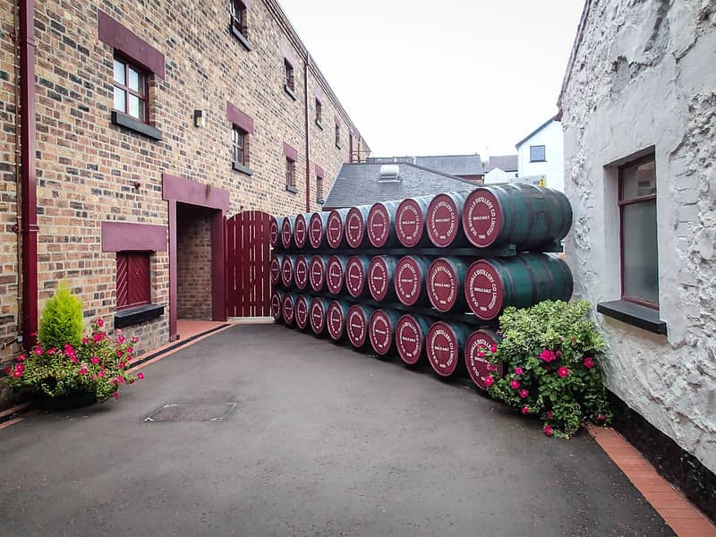 This image has an empty alt attribute; its file name is Bushmills-Whiskey-Distillery-with-Barrels-stacked-up-Credit-Armin-Wiedemann_Flickr.jpg