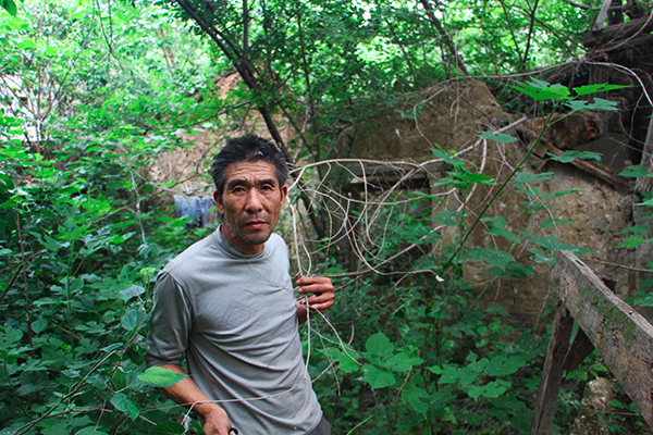 Yang poses before the ruins of his home. (via The Paper)