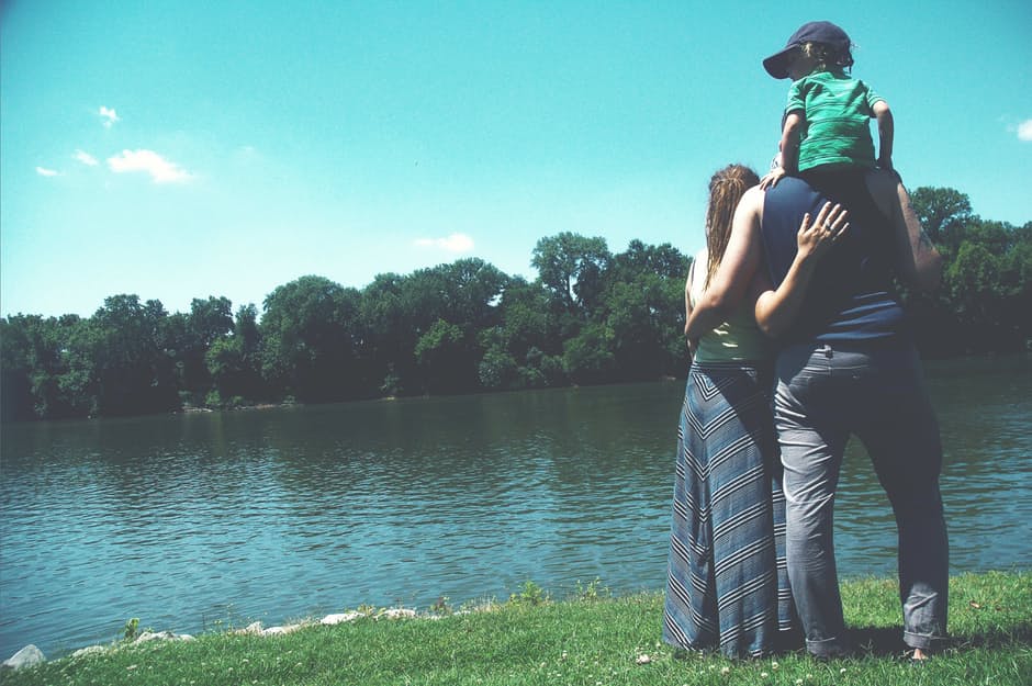 Mother, Father and little boy looking over a calm blue lake