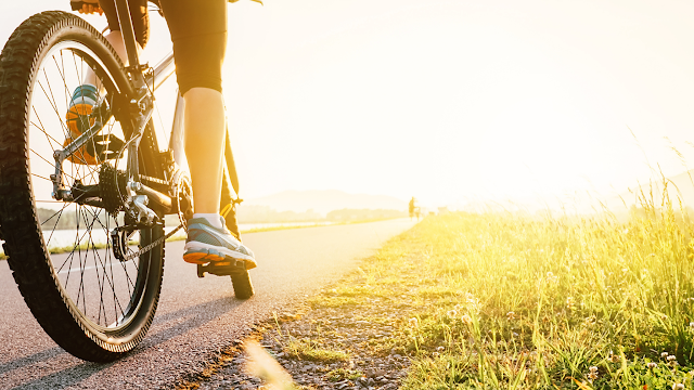 Close up of woman leg on bicycle pedal with sunset in background