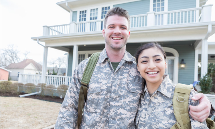 A military couple standing in front of their new home during an off-season PCS move