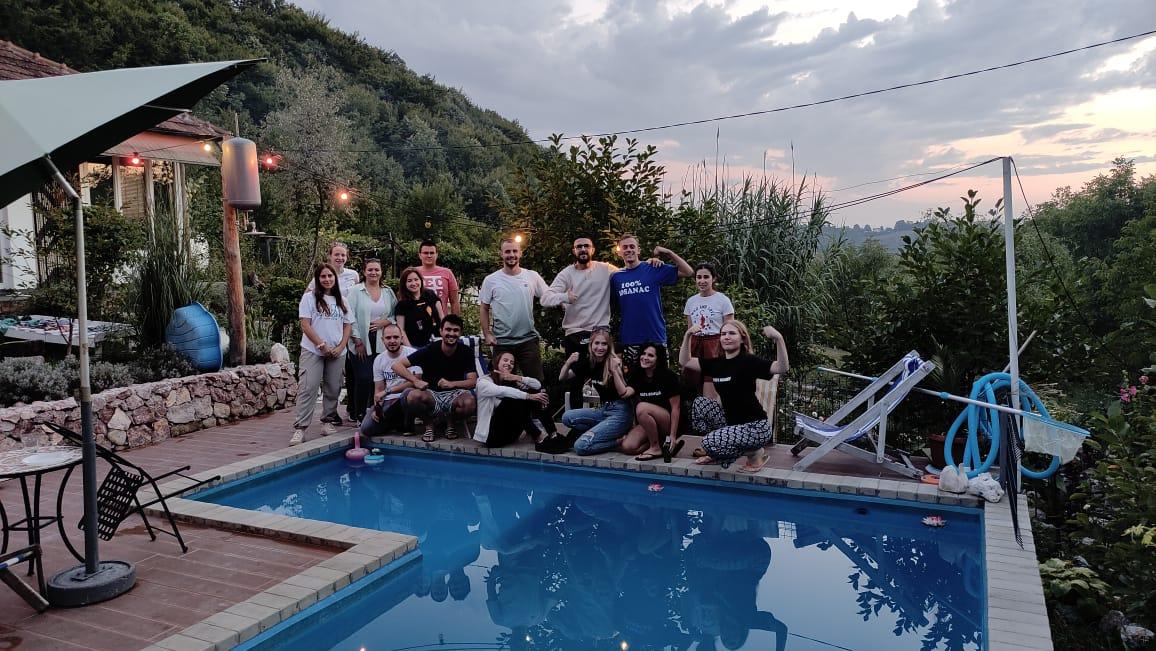 A group of people posing for a photo next to a pool

Description automatically generated