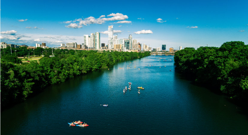 Locals kayak on Lady Bird Lake in Austin, TX, with the city skyline in the distance. 