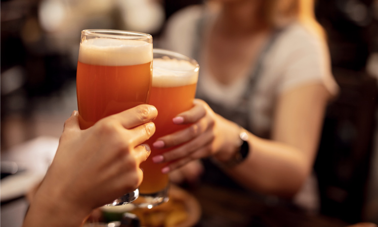 Friends clink their beer glasses together while out on the town in Milwaukee, WI