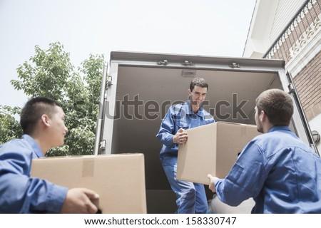 Three men loading boxes into a closed van.