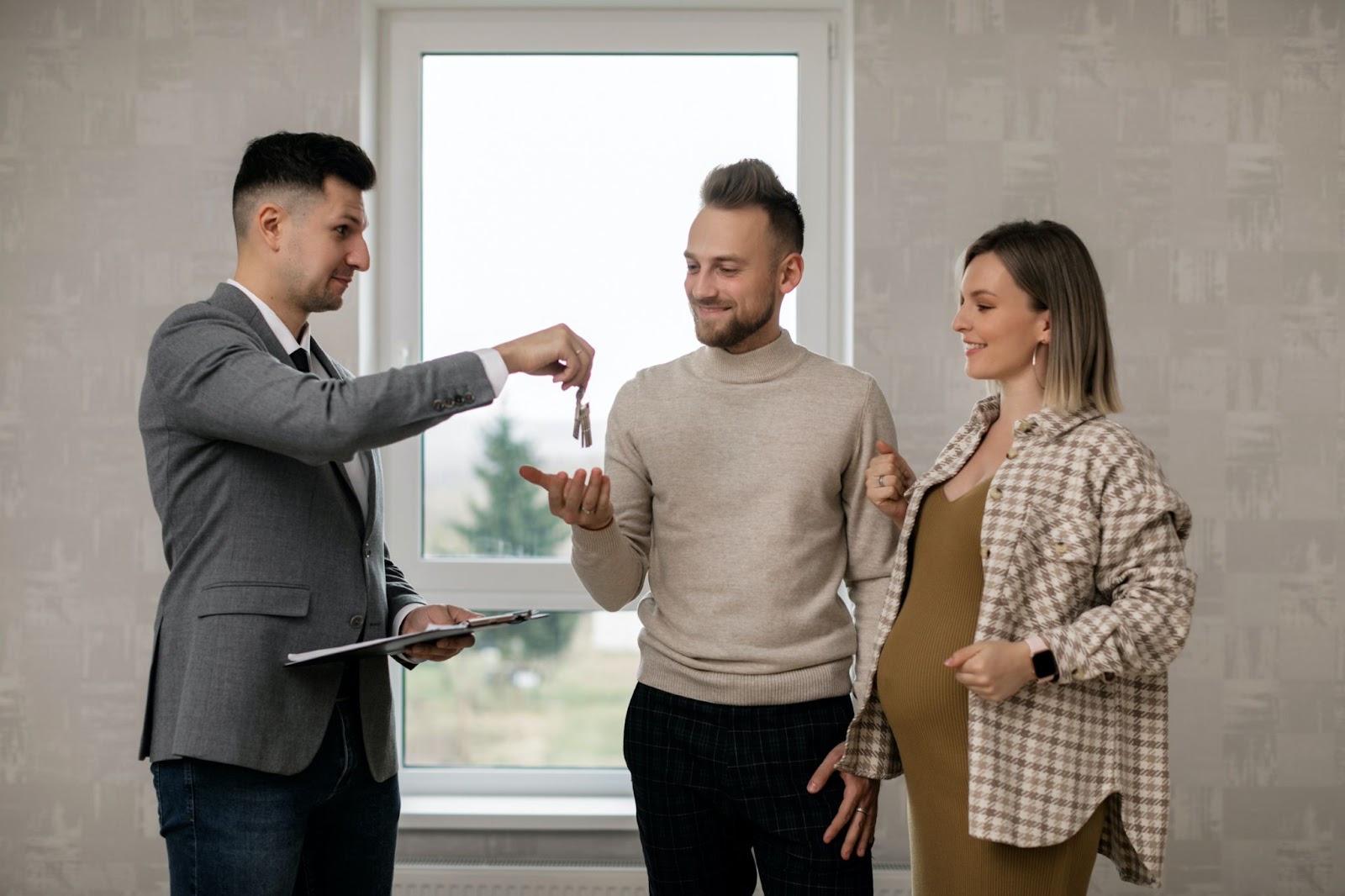 A real estate agent handing the key to the new homeowners.