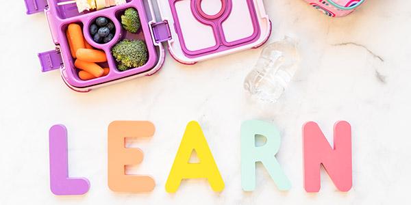 Learn in play letters and lunch box with blueberries, broccoli and carrots.