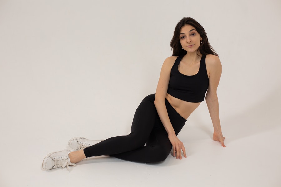 Lady posing in a black crop top and black leggings