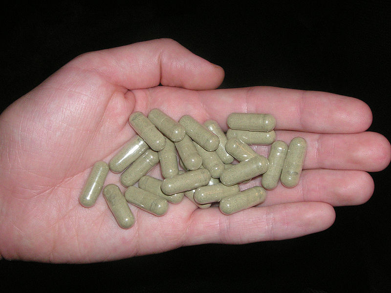 An individual holding Kratom pills