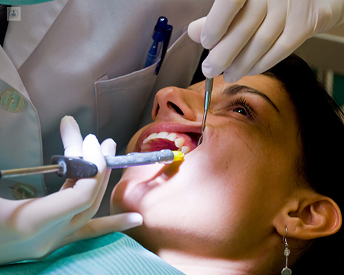 Primer plano del rostro de una paciente mientras el dentista le pincha - Regeneración ósea dental by Top Doctors