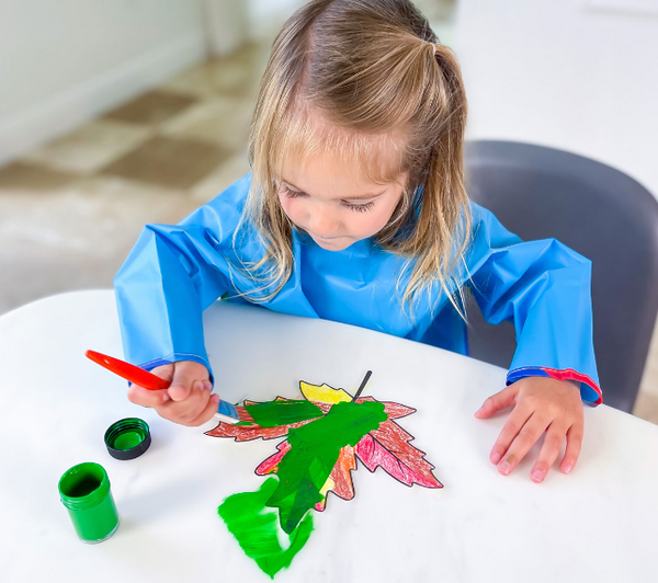 Child painting leaves to use in an autumn preschool theme class