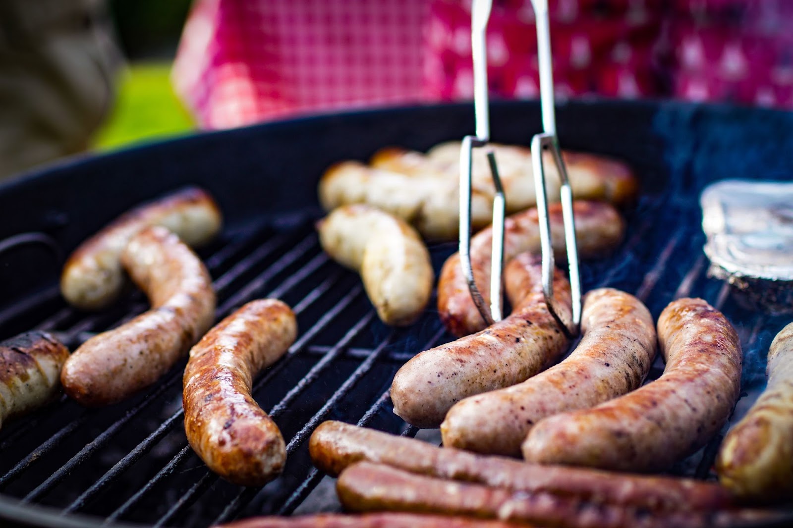 Different types of sausages being cooked on a grille.