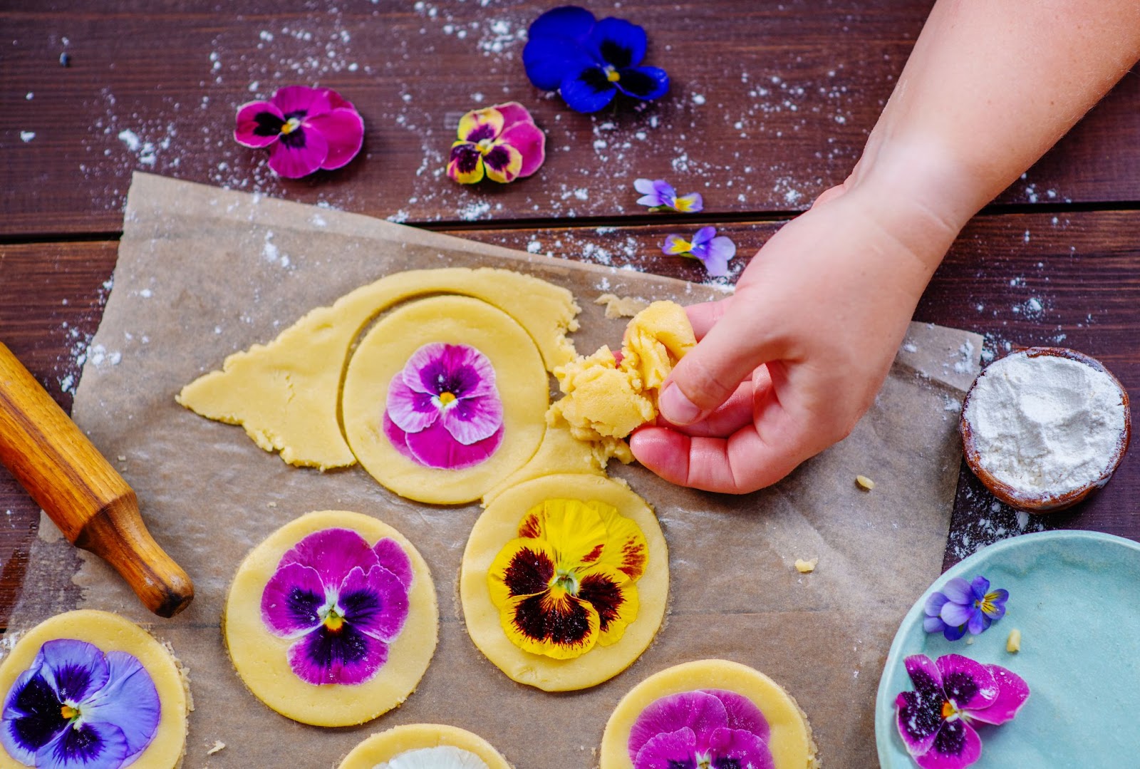 A person using Edible flowers during their baking process.
