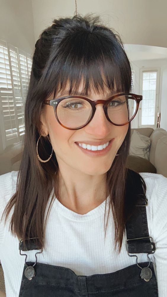 smiling lady with glasses wearing long hair with bangs