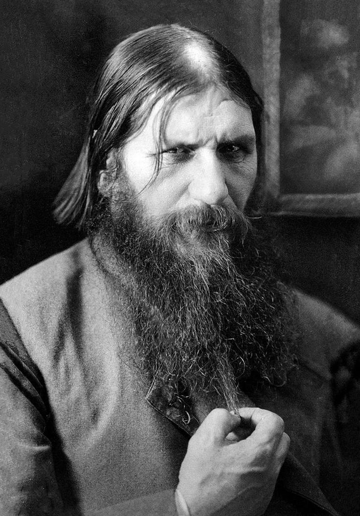 Photograph of Rasputin, glaring at the viewer and holding the end of his long beard.