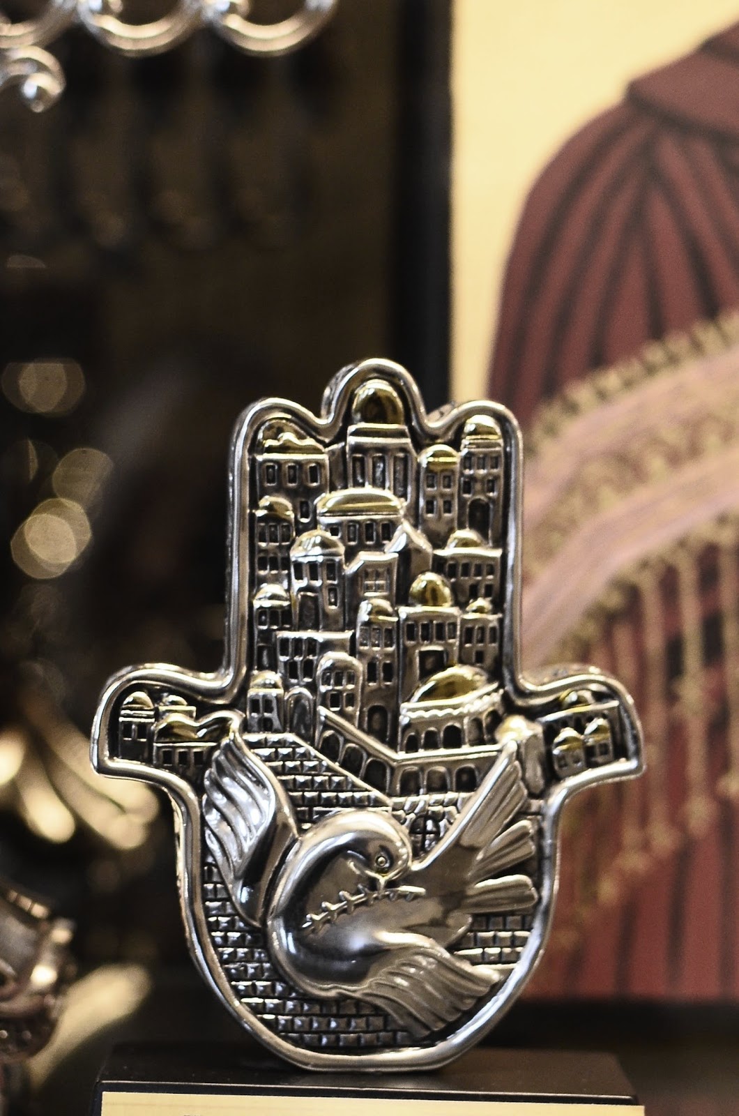 Hamsa with carved metal city and bird illustrations