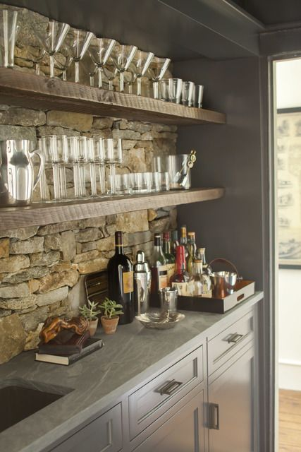 basement bar area with open shelving, stacked stone backsplash, grey shaker cabinets and sink