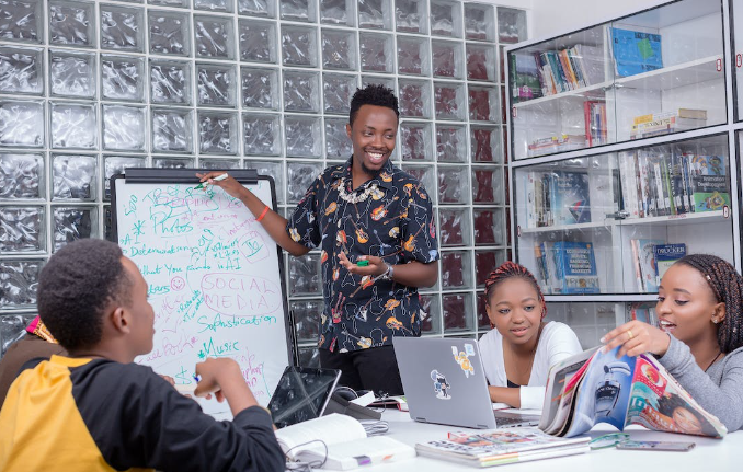 A teacher teaching a group of students on a white board

