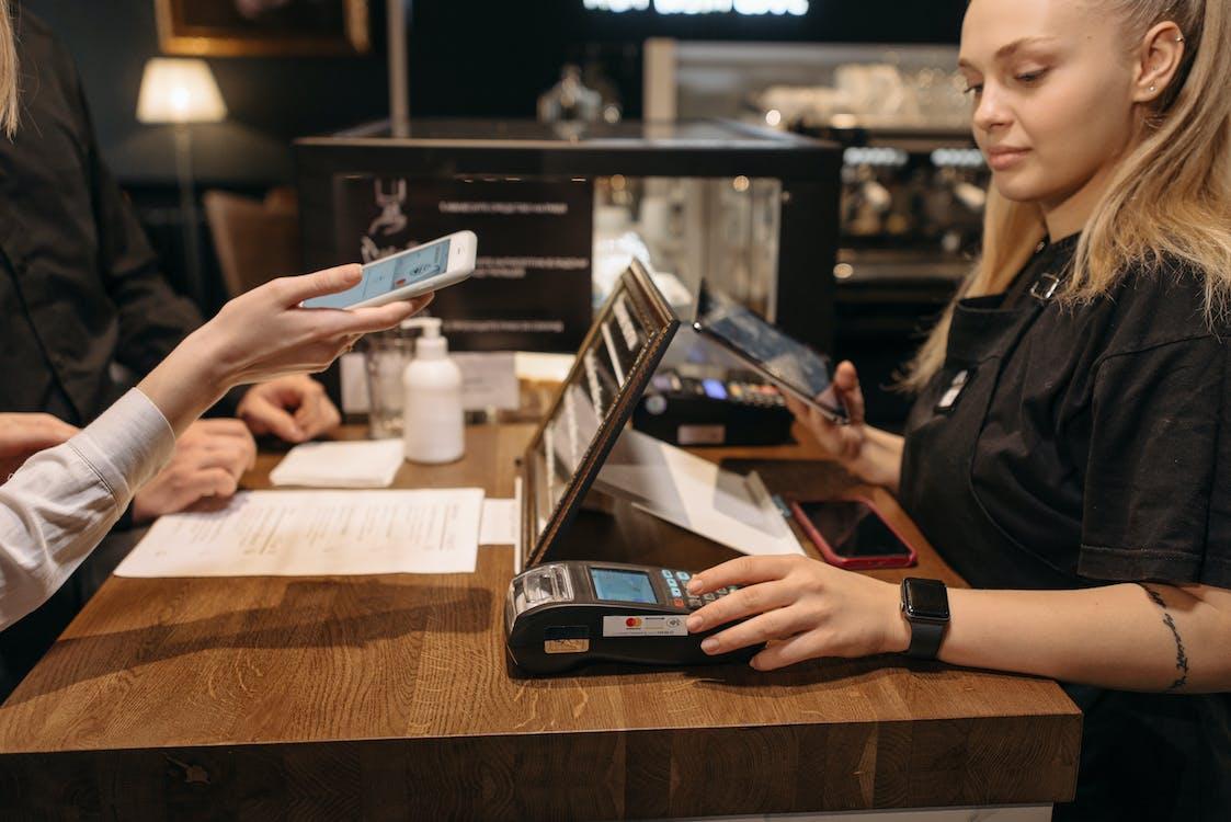 Free A Woman in Black Shirt Using a Payment Terminal at the Counter Stock Photo