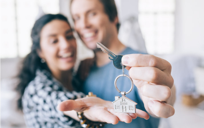 A smiling couple shows off the key to their new fixer-upper house. 