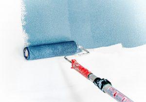 A blue painting roller on a white wall.