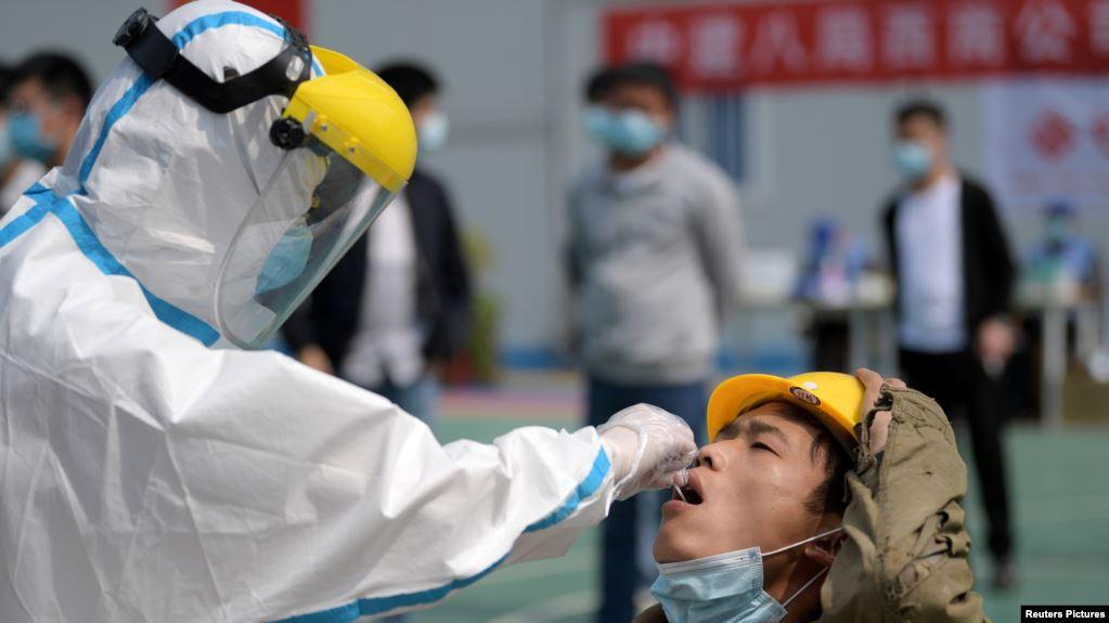 武汉一位医护人员正在对一名建筑工人采取进行核酸检测的样本。