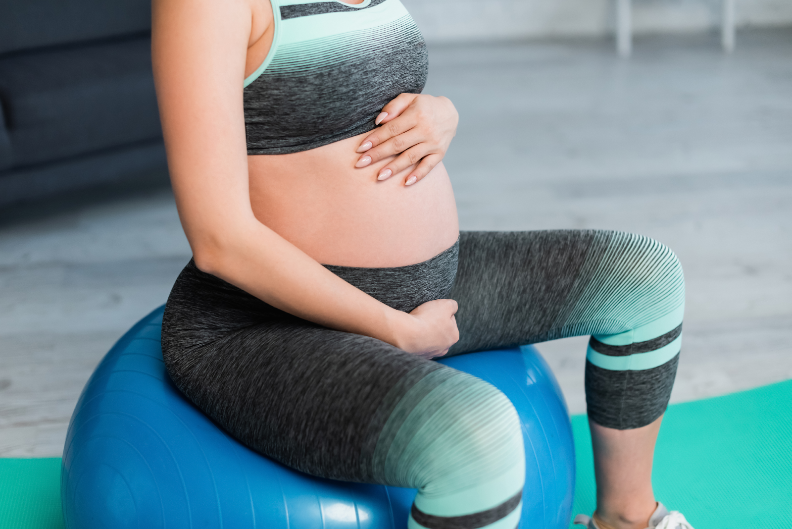 mulher realizando exercícios para aliviar dor nas costas na gravidez em cima de uma bola de yoga 