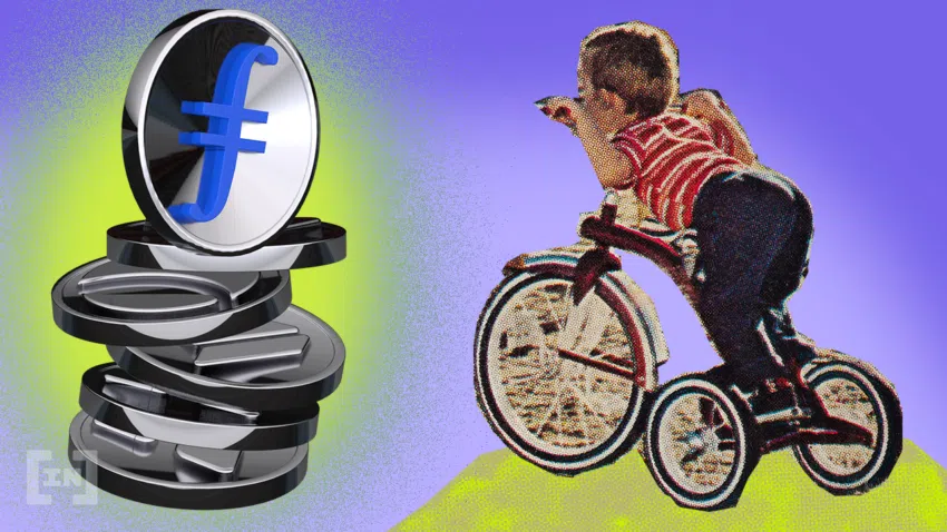Ein Stapel Kryptocoins ist zu sehen, auf dem ganz oben eine Filecoin steht. Ein kleiner Junge lehnt sich auf seinem Dreirad nach vorne und guckt die Krypto-Coin an.