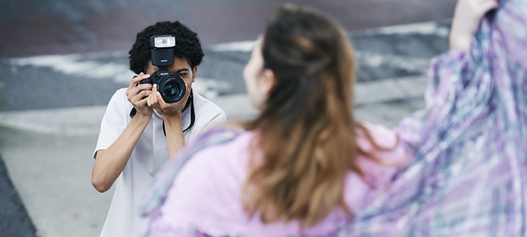 A man taking a snapshot outdoors with a model