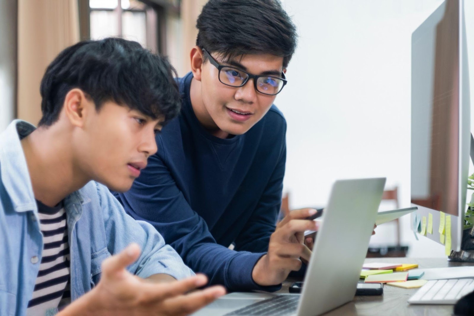 Graphic designers discussing digital designs while pointing on laptop screen