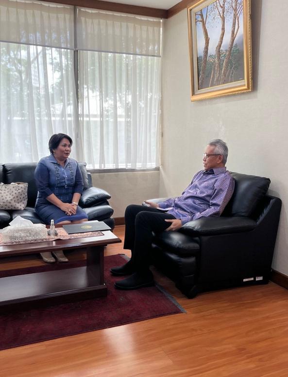 Two people sitting on a couchDescription automatically generated with medium confidence