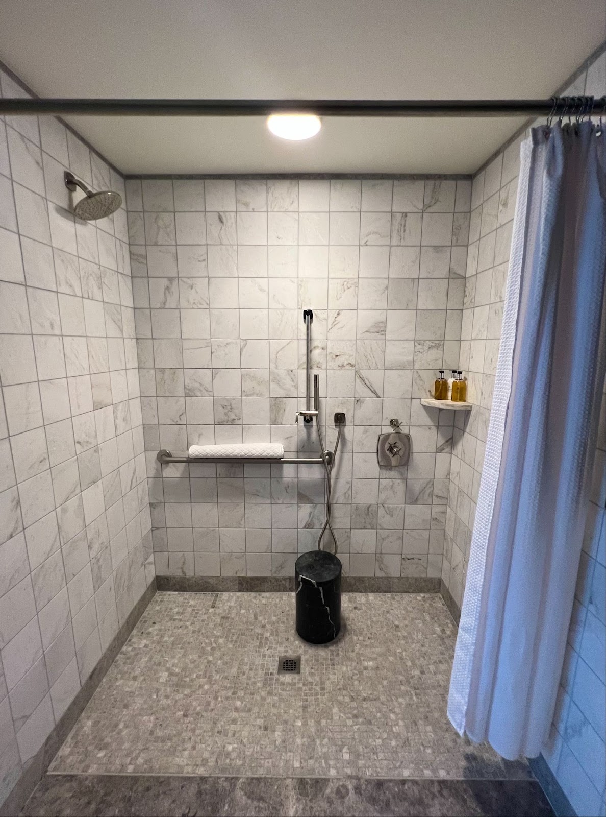 a shower with a black trash can