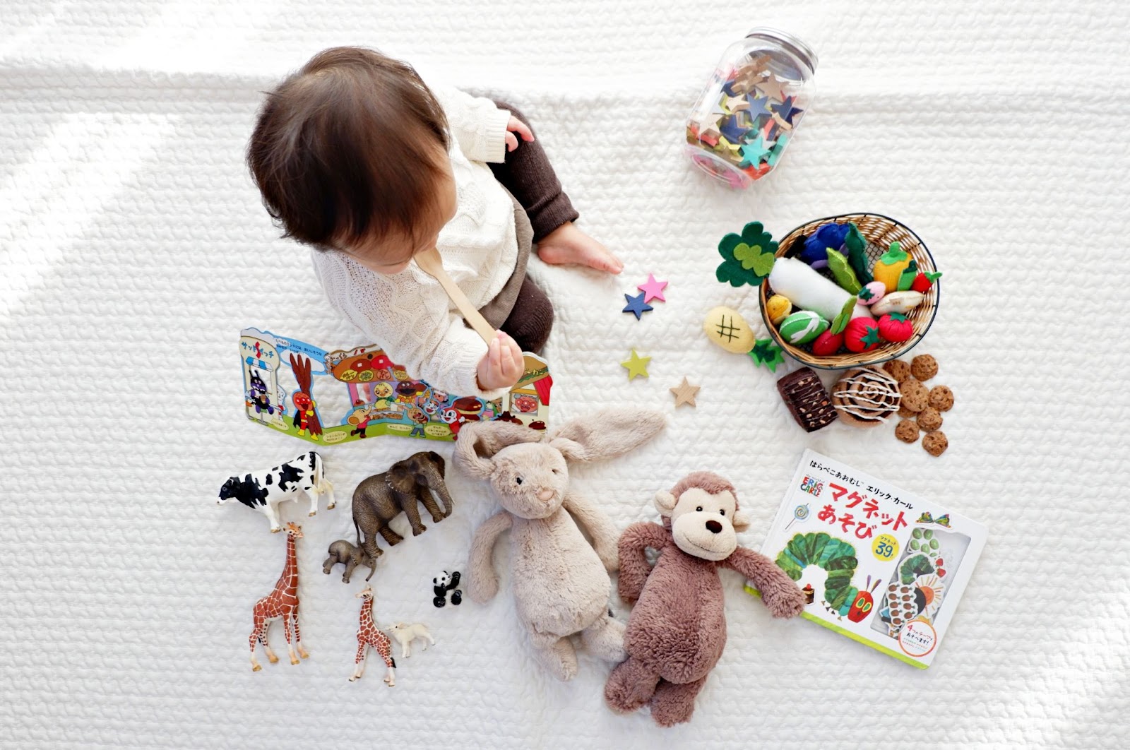 A baby sitting up surrounded by toys.