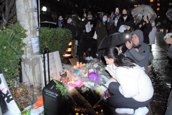 Người biểu tình đặt hoa trước lãnh sự quán Trung Quốc để tỏ lòng thương tiếc với những nạn nhân thiệt mạng trong vụ cháy chung cư ở thủ phủ Ô Lỗ Mộc Tề của Tân Cương, ở Toronto hôm 27/11/2022. (Ảnh: Michelle Hu/The Epoch Times)