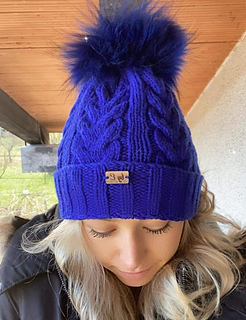 electric blue hat with fur pom pom on woman outside