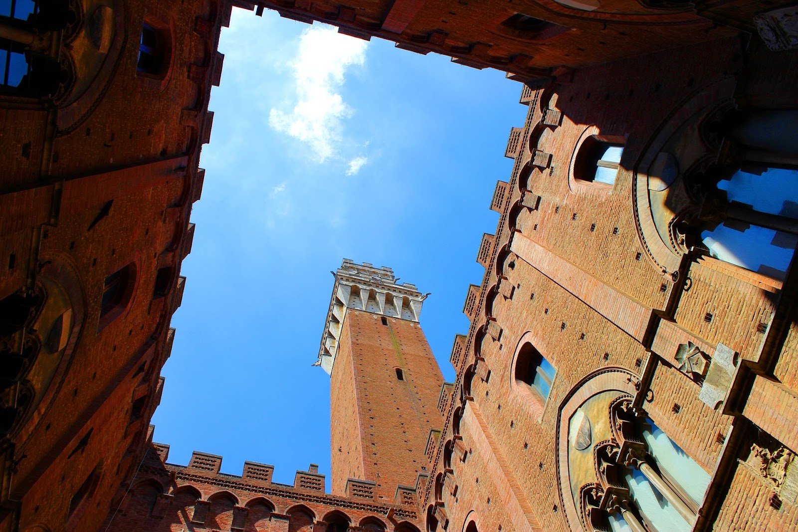 torre del mangia red brick medieval tower symnetrical photo seen from nearby square in siena italy