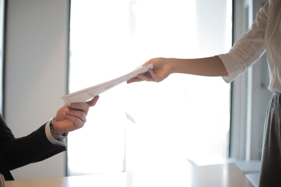 job applicant handing her documents and resume to employer during interview