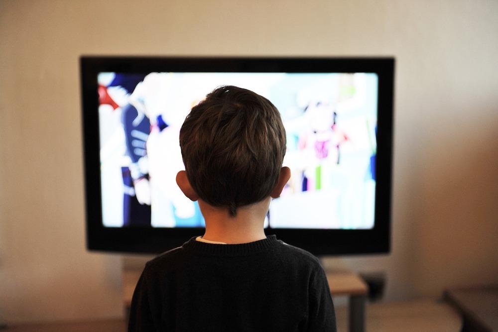 テレビの画面を見ている少年中程度の精度で自動的に生成された説明