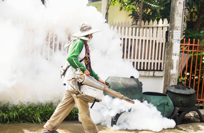 man using thermal fog machine to protect mosquito spreading